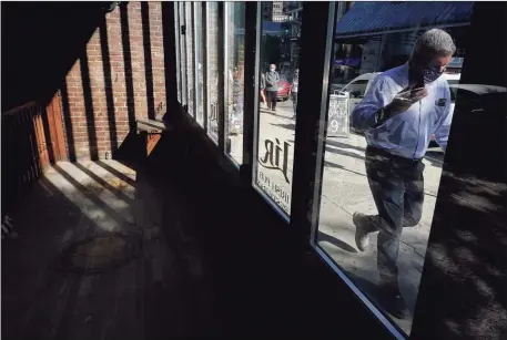  ?? Associated Press ?? A passer-by walks past an empty restaurant, left, Tuesday in Boston. The number of Americans seeking unemployme­nt benefits fell slightly last week to a still-high 840,000, evidence that job cuts remain elevated seven months into the pandemic recession.