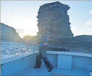  ?? JULIE COLLINS/CAPE BRETON POST ?? Jonathan Squires on board Small Change uses a gaff to snag the line for a lobster trap next to the Bird Islands.