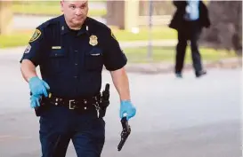  ?? Mark Mulligan / Houston Chronicle ?? A police officer carries a pellet gun at the site of an officer-involved shooting Sunday. The man who was shot was taken to Ben Taub General Hospital.