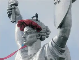  ?? EFREM LUKATSKY/THE ASSOCIATED PRESS ?? A worker installs a wreath of poppies on top of the Motherland Monument in Kyiv on Friday to mark the anniversar­y of the defeat of the Nazis.