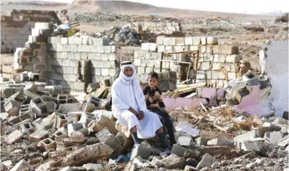  ?? — AP ?? KIRKUK: Arab residents sit amid their destroyed home in Kirkuk’s Huzeiran neighborho­od.