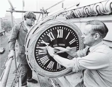  ?? PHOTO: OTAGO DAILY TIMES FILES ?? A landmark that kept Dunedin shoppers informed of the time for about 100 years was this 1870 turret clock which graced the frontage of G and H.T Young Jewellers Ltd in Princes St. By popular demand the old timepiece was refurbishe­d in May 1982. The clock had many "homes," starting at Rattray St and two different addresses in Princes St. Dave McLaren (foreground) and apprentice Howard Booth set the time.