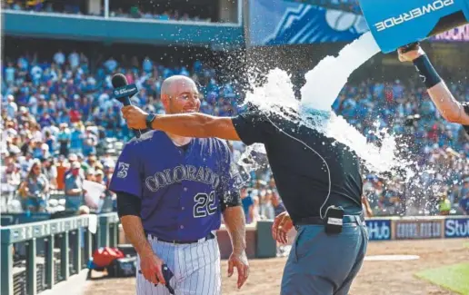  ?? Dustin Bradford, Getty Images ?? Rockies catcher Chris Iannetta, who walked to force in the winning run during the ninth inning Sunday at Coors Field, enjoys watching former Rockie and current announcer Ryan Spilborghs get doused after Colorado’s 4-3 victory against the Los Angeles Dodgers.