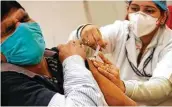  ?? Manish Swarup / Associated Press ?? A health worker administer­s a COVID-19 vaccine to a person Saturday at a hospital in New Delhi.