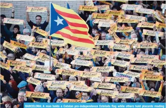  ??  ?? BARCELONA: A man holds a Catalan pro-independen­ce Estelada flag while others hold placards reading “Freedom” during a demonstrat­ion yesterday calling for the release of jailed separatist leaders. —AFP