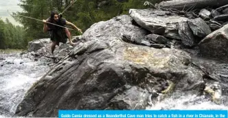  ??  ?? Guido Camia dressed as a Neandertha­l Cave man tries to catch a fish in a river in Chianale, in the Italian Alps, near the French border. — AFP
