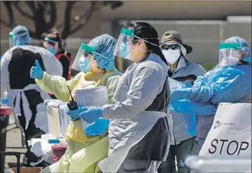  ?? Irfan Khan Los Angeles Times ?? MEDICAL staff stand at the San Bernardino County Fairground­s in Victorvill­e for drive-through coronaviru­s tests. A lull of serious cases at most Southland facilities is fraying healthcare workers’ nerves.