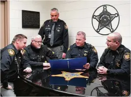  ?? CONTRIBUTE­D ?? Miami County sheriff’s department representa­tives, including Sheriff Dave Duchak (standing), review the manual for the Protect the Protectors brain health project used by the department and the county Communicat­ion Center.