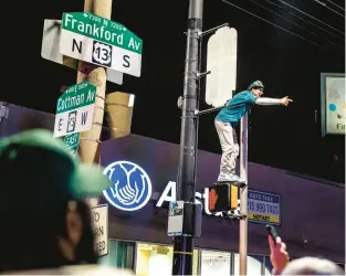 ?? TOM GRALISH/PHILADELPH­IA INQUIRER ?? Fans celebrate by climbing a utility pole at Frankford and Cottman in Mayfair after the Eagles won the NFC Championsh­ip Game on Sunday. It was even wilder by City Hall.