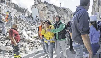  ?? ALESSANDRA TARANTINO / AP ?? A woman is comforted as she walks through earthquake rubble in Amatrice, Italy, Wednesday. The devastatin­g quake collapsed buildings onto residents and tourists as they slept.