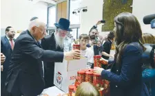  ?? (Marc Neiman/GPO) ?? PRESIDENT REUVEN RIVLIN helps pack a Passover care package as Israel Prize laureate Rabbi Yitzchak Dovid Grossman and volunteers look on at the President’s Residence in Jerusalem yesterday.