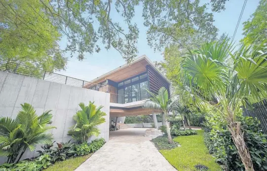  ?? ANGEL NICOLAS WITH COMPASS/COURTESY PHOTOS ?? Designed by Miami architect Gabriel Lopez, the 9,753-square-foot home is unusual for Miami because it has bedrooms on the ground floor, including a bedroom hidden by a wood wall, and main living areas on the second.