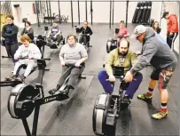  ??  ?? Right: Instructor Rob Lavigne of Hammonasse­t CrossFit of Madison, with Vito of Clinton on the rowing machine, right.