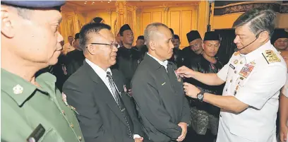  ??  ?? JASAMU DIKENANG: Ahmad Kamarulzam­an memakaikan Pingat Jasa Malaysia kepada salah seorang veteran TLDM di Kuching, semalam.