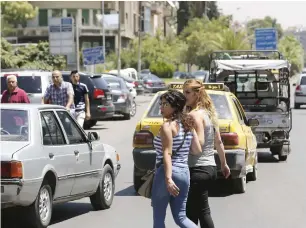  ?? AFP ?? Syrian women cross a road in the capital Damascus. Syrian authoritie­s have begun removing security barriers improving traffic flow in the capital. —
