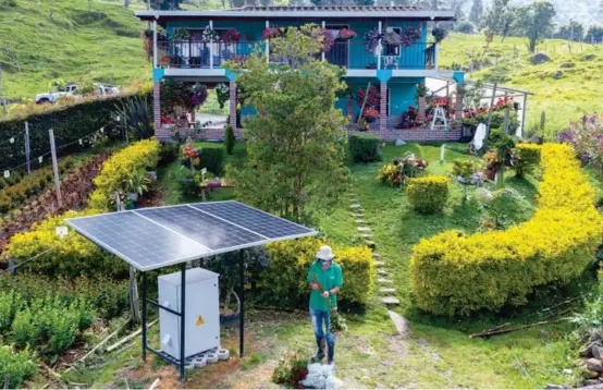  ?? FOTOS ?? Don Édgar organiza unas flores junto a los paneles solares que instalaron en Rancho Viejo para surtir de energía a 90 bombillos led. Al fondo el lugar donde vive junto a su familia en la vereda San José de la montaña de San Cristóbal.