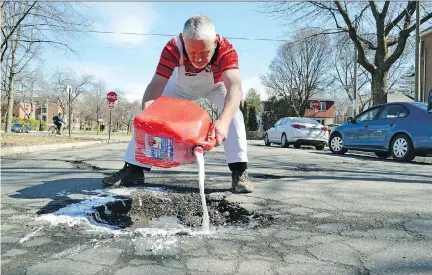  ?? ISAAC OLSON ?? Councillor Jeremy Searle pours water-soluble white paint around a pothole on Fielding Ave. in the Loyala district to warn drivers of the danger to their vehicles. Searle says he’s also protesting what he feels has been a lack of investment in the...