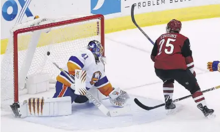  ??  ?? Arizona Coyotes centre Nick Cousins scores the OT game winner against New York Islanders goaltender Jaroslav Halak Monday in Glendale, Ariz.