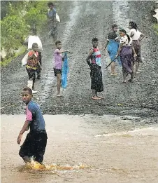  ?? ?? Qelekuro villagers cross a flooded portion of road in Tailevu North.