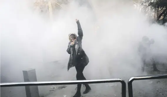  ?? Picture: AFP ?? [CAPTION] TEARY-EYED. A demonstrat­or raises her fist amid the smoke of tear gas at the University of Tehran on Saturday.