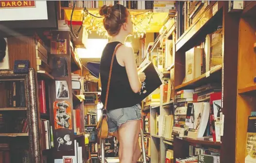  ?? MITCH DAVIS ?? Emma Smreker, 30, scours used book stores looking for something readers have left behind, tucked inside the books. Here she is at Chicago’s Ravenswood Books in July 2017.