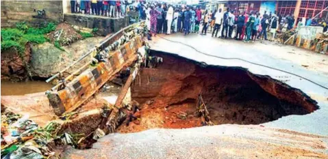  ??  ?? Sympathise­rs watch a bridge that was eroded by Saturday night’s heavy downpour at Oko- Erin area of Ilorin, Kwara State… yesterday.