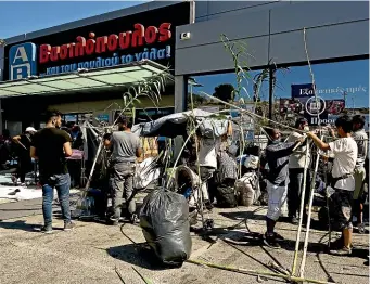  ?? GETTY IMAGES ?? Refugees build improvised shelters outside shops close to Lesbos’s capital, Mytilene, after a fire destroyed the Moria refugee camp on the island.