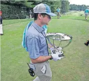  ?? [AP PHOTO] ?? Zach Rosen carries the winner’s trophy from the first tee box during the final round of the Northern Trust golf tournament Sunday in Paramus, N.J.