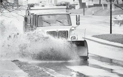  ?? PAUL W. GILLESPIE/BALTIMORE SUN MEDIA GROUP ?? An Anne Arundel County snowplow clears water from a blocked storm drain on Bestgate Road in front of Bestgate Park as cold rain mingled with freezing rain and sleet in Annapolis Tuesday afternoon.