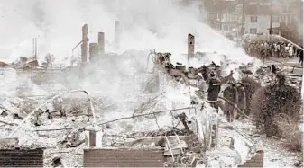  ?? BALTIMORE SUN ?? As morning comes in Cambridge, firefighte­rs train hoses on the remains of the Pine Street Elementary School after the riot in 1967.