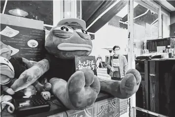  ?? — AFP photo ?? Diners slurp wonton under the watchful gaze of a mask-wearing Pepe the Frog, which has become a mascot of the pro-democracy movement.