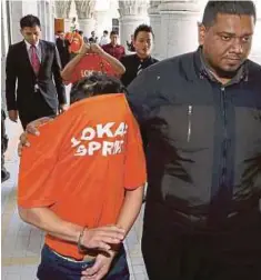  ?? PIC BY AHMAD IRHAM MOHD NOOR ?? The suspects being escorted out of the magistrate’s court in Putrajaya yesterday.