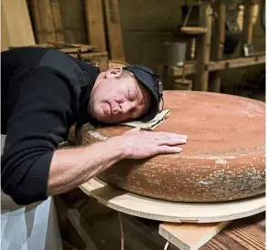  ??  ?? Wampfler lays his head on a wheel of Emmental cheese that is being matured with music playing from small speakers directly below. – AFP