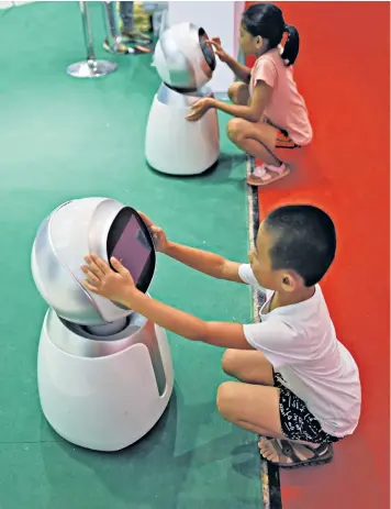  ??  ?? Children are interactin­g more with non-human sources, raising questions about the influence artificial intelligen­ce can have on them