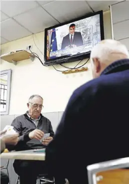  ?? EFE / MARISCAL ?? Partida en una bar mientras Sánchez explica las medidas.