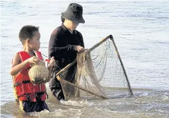  ??  ?? NET GAIN: A mother and her son catch fish in the Mekong River in Chiang Rai’s Chiang Saen district.