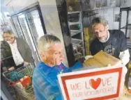  ?? Jeremy Papasso, Daily Camera ?? Glenn Short, left, shops for food as volunteers Ray Meyers, center, and Jim Bush stock the freezer with fresh supplies at the Boulder Emergency Family Assistance Associatio­n food bank on Thursday in North Boulder.