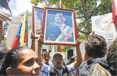  ?? Ariana Cubillos / Associated Press ?? Government supporters carry portraits of the late Hugo Chavez, President Nicolas Maduro’s predecesso­r.