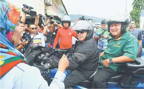  ??  ?? Jamilah (left) gives the thumbs-up to Abang Johari and Uggah (right), who arrived in Lundu town for the Road to Maha 2018 event on the chief minister’s high-powered motorcycle. — Photo by Muhammad Rais Sanusi