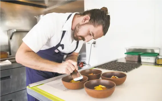  ?? PHOTOS BY LAURA MORTON ?? Michael Warring works on preparing a dish of ocean trout with foie gras, hearts of palm, fennel pollen and popcorn jus. He serves six-course dinners at his Vallejo restaurant.