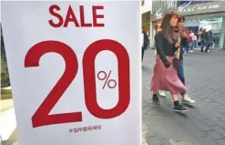  ??  ?? SEOUL: Women walk past a commercial sign advertisin­g a sale at a shopping district in Seoul yesterday. Asia’s fourth-largest economy grew slightly more than previously thought in each of the past two years, South Korean authoritie­s said yesterday. — AFP