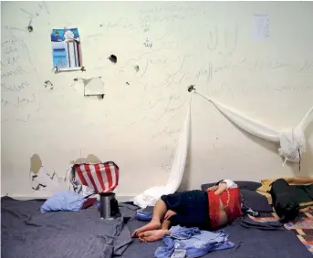  ??  ?? A boy sleeps inside the disused Elliniko airport where refugees and migrants are temporaril­y housed in Athens, in a file photo.