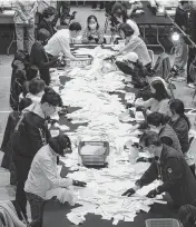  ?? LEE YOUNG-HO Sipa USA/USA TODAY NETWORK ?? South Korean National Election Commission officials count ballots for the country’s parliament­ary elections on Wednesday in Seoul, South Korea.