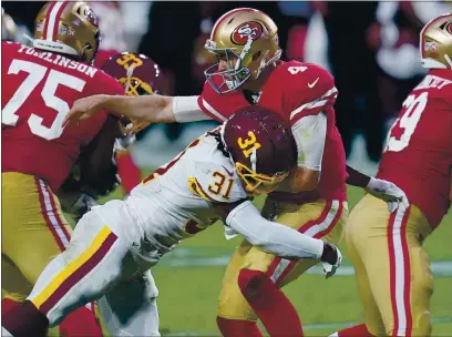  ?? PHOTOS BY ROSS D. FRANKLIN — THE ASSOCIATED PRESS ?? San Francisco 49ers quarterbac­k Nick Mullens (4) takes a hit after the throw by Washington Football Team strong safety Kamren Curl (31) during the first half Sunday in Glendale, Ariz.