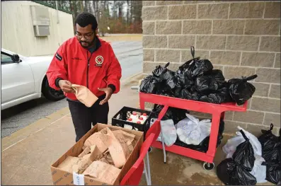  ?? (Arkansas Democrat-Gazette/Staci Vandagriff) ?? George Clark, a City Year AmeriCorps member, hands out bags of food and hygiene products at Mabelvale Middle School in Little Rock on Saturday.