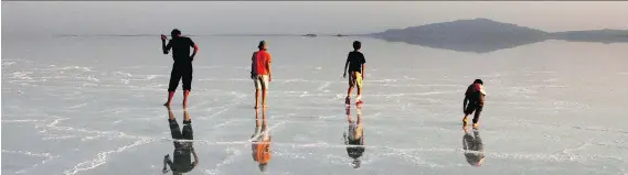  ??  ?? Travellers admire their reflection­s in the massive salt flats of the Afar Region. Salt is the main resource of the Danakil, and about 700 registered miners work in the Ethiopian lowland.