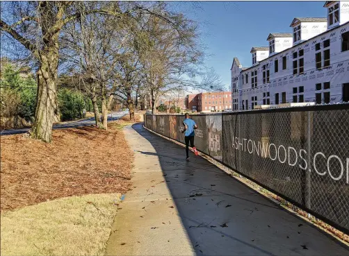  ?? TY TAGAMI / TY.TAGAMI@AJC.COM ?? Brookhaven is building its path network one property at a time by requiring developers to either build segments in front of their projects or pay into a fund, depending on whether they are building along a planned route. A jogger is seen Tuesday on one new stretch on North Druid Hills Road.