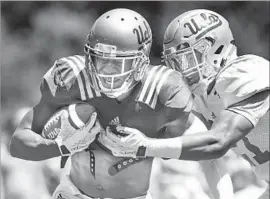  ?? Ringo H.W. Chiu For The Times ?? UCLA TIGHT END Austin Roberts, left, battling Tahaan Goodman in a spring scrimmage, is still haunted by a dropped pass in 2016 opener against Texas A&M.