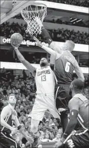  ?? Ronald Martínez Getty Images ?? CLIPPERS FORWARD Paul George tries to score against the long arm of the Mavericks’ Kristaps Porzingis. George had 26 points in 29 minutes.