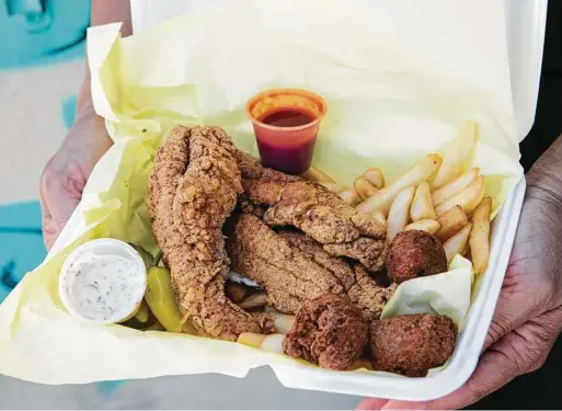  ?? Jessica Sample / New York Times ?? Fried catfish with hush puppies and french fries at Mel’s Fish Shack in Los Angeles. Side dishes showcase regional difference­s in the tradition-soaked fish fry and, in addition to those featured at Mel’s, often include potato salad, meatless spaghetti and coleslaw.